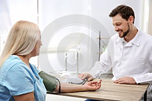 Doctor checking mature woman`s pulse with medical device