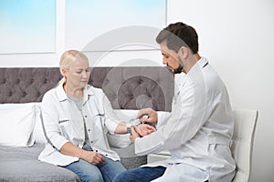 Doctor checking mature woman`s pulse with medical device