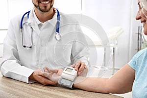 Doctor checking mature woman`s pulse with medical device in hospital