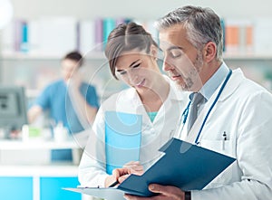 Doctor checking medical records with his assistant
