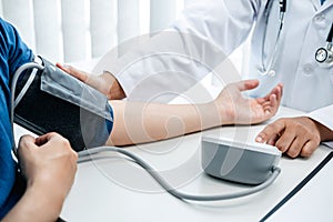 Doctor is checking the patient blood pressure in his hospital office