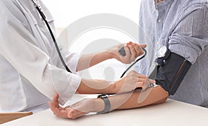 Doctor checking patient`s blood pressure in hospital, closeup.