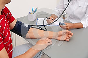 Doctor checking patient`s blood pressure at table