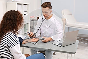 Doctor checking patient`s blood pressure at table