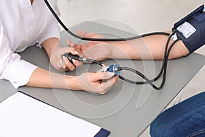 Doctor checking patient`s blood pressure at table in office