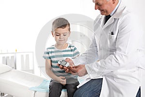 Doctor checking patient`s blood sugar level with digital glucometer in hospital