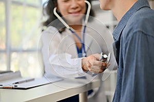 A doctor is checking a patient's heartbeat with a stethoscope during a medical checkup