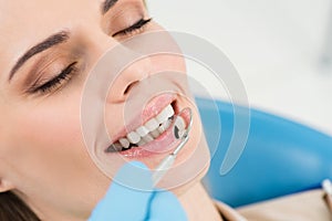 Doctor checking patient teeth with mirror in modern