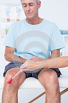 Doctor checking reflexes of the knee of her patient