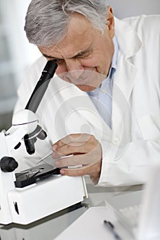 Doctor checking sample thorugh microscope photo