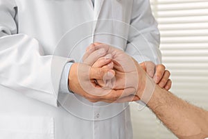 Doctor checking senior man`s pulse in hospital, closeup