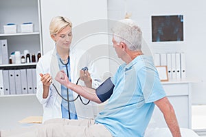 Doctor checking senior mans blood pressure