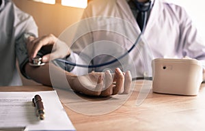 Doctor checking a senior patient`s blood pressure in office room