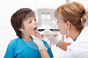 Doctor checking the throat of a young boy