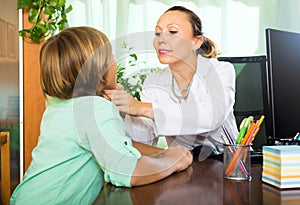 Doctor checking thyroid of teenager