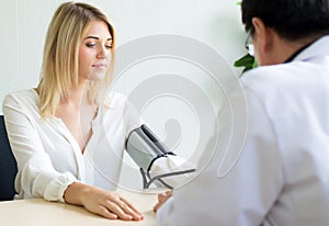 Doctor checking to beautiful caucasian woman patient blood pressure in hospital,Heart rate pressure gauge