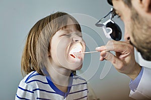 Doctor checking tonsils of patient at hospital