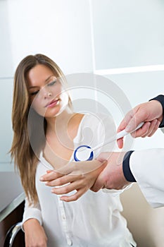 Doctor checking wrist with reflex round hammer to woman