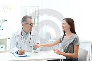 Doctor checking young woman`s pulse with medical device