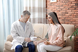 Doctor checking young woman`s pulse with medical device