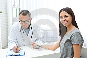 Doctor checking young woman`s pulse with medical device