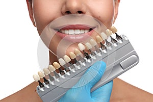 Doctor checking young woman`s teeth color on white background, closeup. Cosmetic dentistry