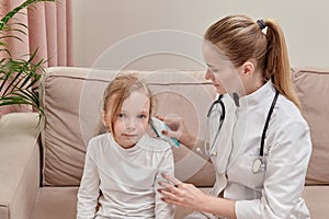 The doctor checks the girl hearing. Using an otoscope.
