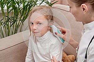 The doctor checks the girl hearing. Using an otoscope.