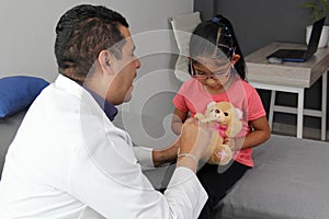 Doctor checks his girl patient with ASD, she have teddy bear that he carries as an attachment or transitional object