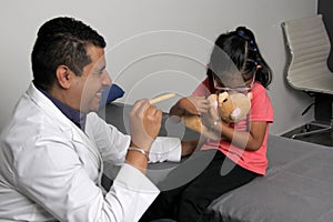 Doctor checks his girl patient with ASD, she have teddy bear that he carries as an attachment or transitional object