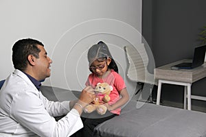 Doctor checks his girl patient with ASD, she have teddy bear that he carries as an attachment or transitional object