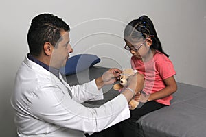 Doctor checks his girl patient with ASD, she have teddy bear that he carries as an attachment or transitional object