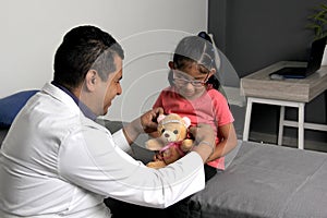 Doctor checks his girl patient with ASD, she have teddy bear that he carries as an attachment or transitional object