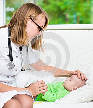 Doctor checks the temperature of baby touching his forehead