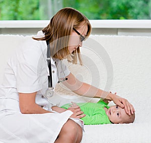 Doctor checks the temperature of baby touching his forehead