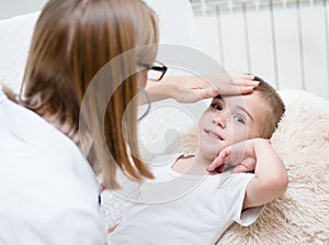 Doctor checks the temperature of a boy touching his forehead