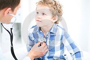 Doctor and child patient. Physician examines little boy by stethoscope. Medicine and children`s therapy concept