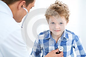 Doctor and child patient. Physician examines little boy by stethoscope. Medicine and children`s therapy concept