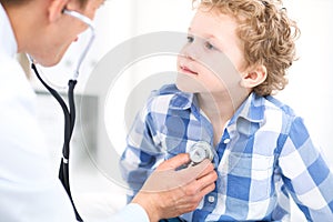 Doctor and child patient. Physician examines little boy by stethoscope. Medicine and children`s therapy concept