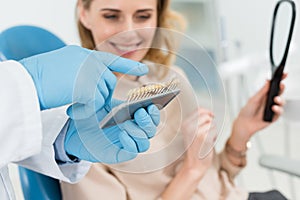 Doctor choosing tooth implants with female patient in modern