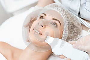 The doctor cleanses the woman`s skin with a special medical device. The woman came to procedure of laser hair removal. photo