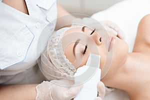 The doctor cleanses the woman`s skin with a special medical device. The woman came to procedure of laser hair removal.
