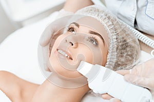 The doctor cleanses the woman`s skin with a special medical device. The woman came to procedure of laser hair removal.