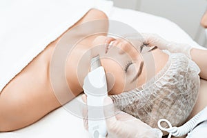 The doctor cleanses the woman`s skin with a special medical device. The woman came to procedure of laser hair removal.