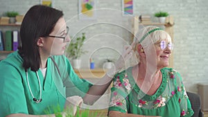 Doctor in the clinic helps to put a hearing aid in the ear of elderly woman close up