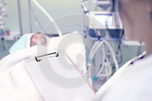 Doctor with clipboard against the patient's bedside