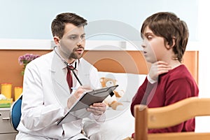 Doctor with clipboard examining child patient with sore throat