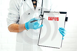 Doctor with clipboard on a white background with a pen shows the name of the disease LUPUS