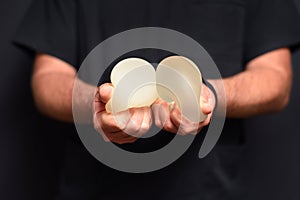 The doctor is clutching breast augmentation implants in his hands