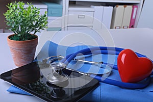 Doctor coat with medical stethoscope and red heart on the desk